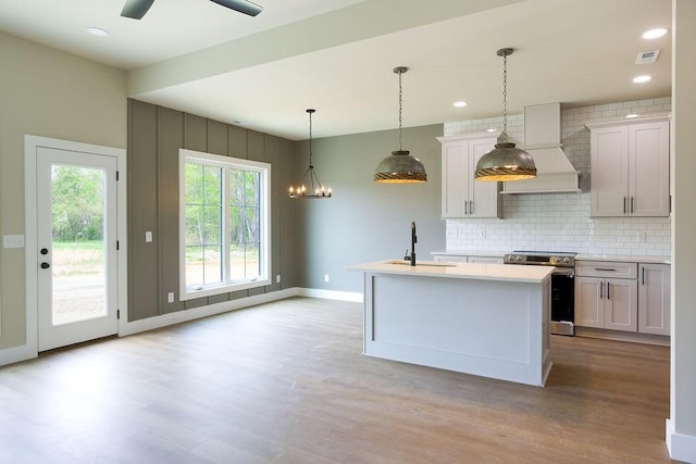 kitchen featuring electric range, light countertops, light wood-type flooring, tasteful backsplash, and visible vents