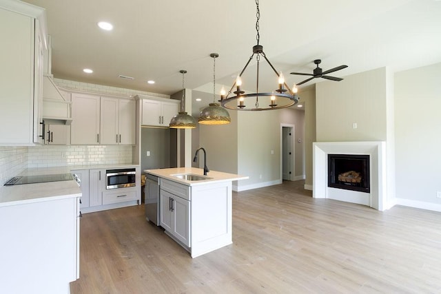 kitchen featuring decorative backsplash, open floor plan, light countertops, a sink, and stainless steel appliances
