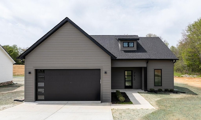 view of front of house with an attached garage, roof with shingles, and concrete driveway