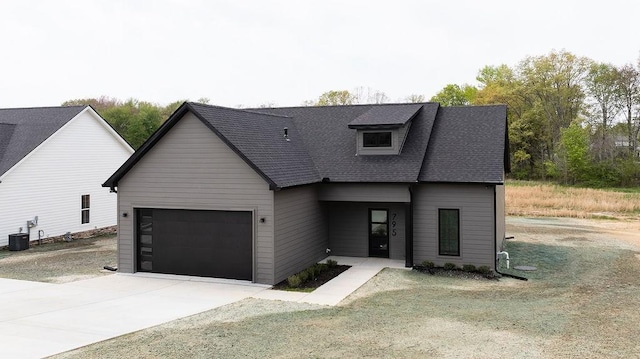 view of front of property with driveway, central AC unit, roof with shingles, and a garage