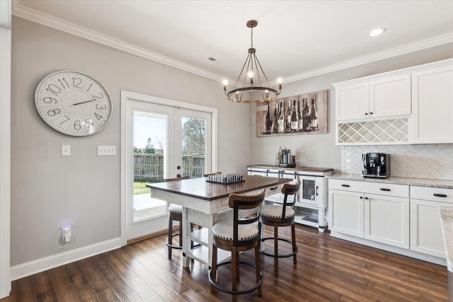 dining room with dark wood-type flooring, baseboards, ornamental molding, french doors, and a notable chandelier