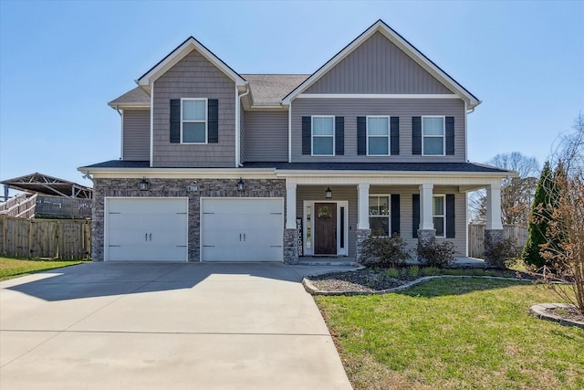 craftsman inspired home featuring fence, a front yard, driveway, stone siding, and an attached garage