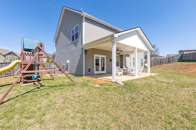 back of property with a playground, ceiling fan, french doors, a fenced backyard, and a patio area