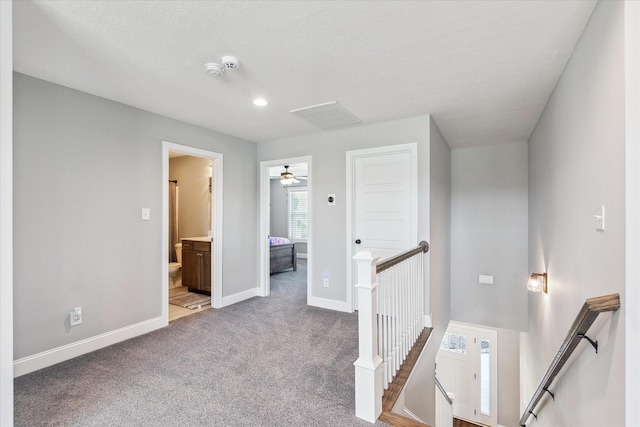 hallway with baseboards, an upstairs landing, carpet floors, and visible vents