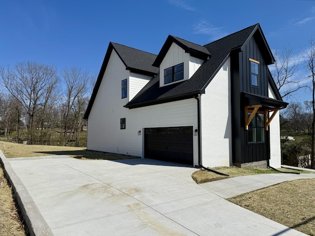 view of side of home with an attached garage, brick siding, board and batten siding, and driveway