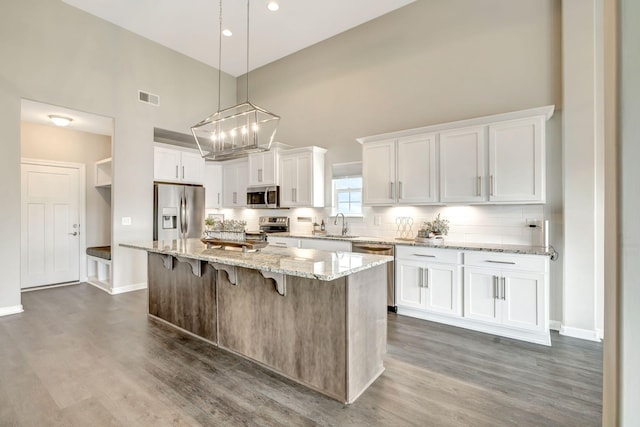 kitchen featuring white cabinets, visible vents, stainless steel appliances, dark wood-style floors, and backsplash