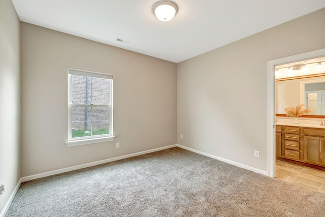 unfurnished bedroom featuring light carpet, baseboards, visible vents, and connected bathroom