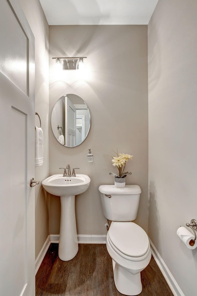 bathroom with baseboards, toilet, and wood finished floors