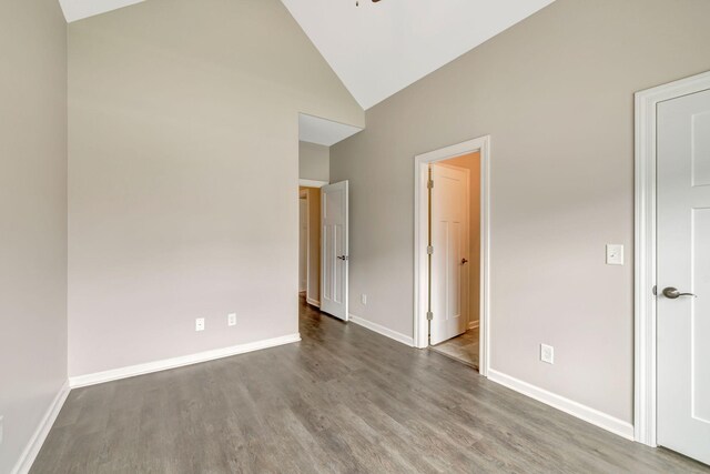 unfurnished bedroom featuring baseboards, high vaulted ceiling, and wood finished floors