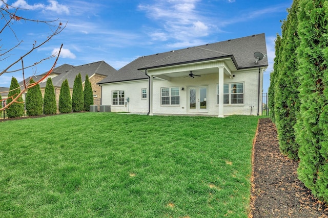 rear view of house featuring a fenced backyard, a ceiling fan, brick siding, a lawn, and french doors