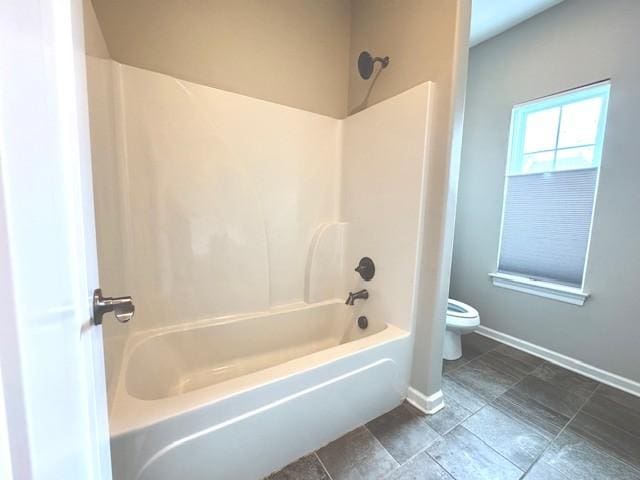 bathroom with shower / bathing tub combination, baseboards, and toilet