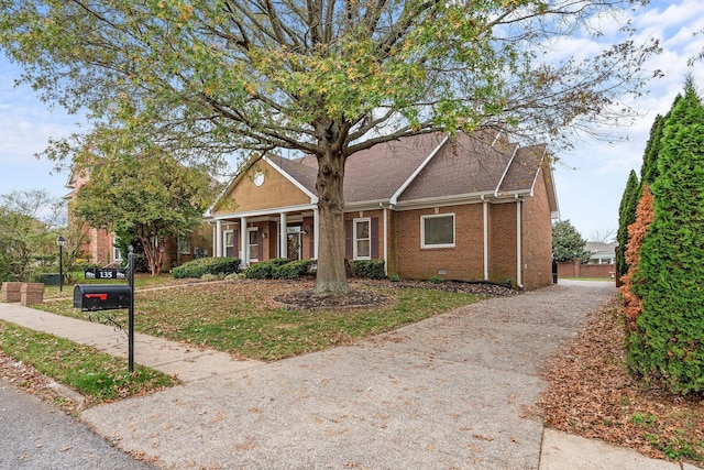 view of front facade featuring brick siding, driveway, and crawl space