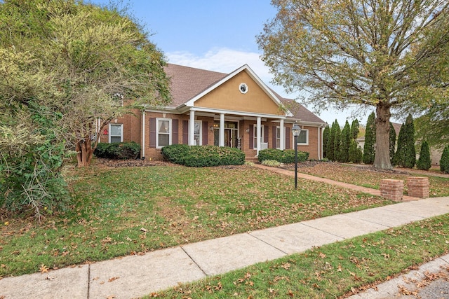 view of front of property with brick siding, a porch, and a front yard