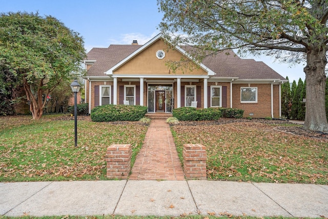 view of front of home featuring a front yard, brick siding, covered porch, and a shingled roof