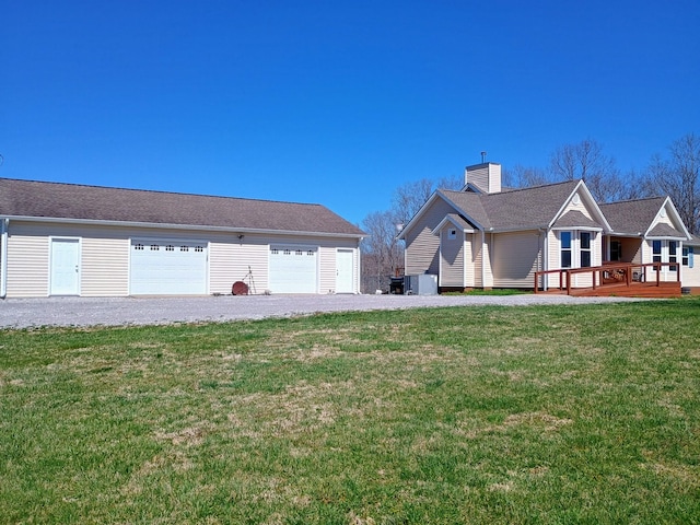 exterior space featuring a lawn, an outdoor structure, a deck, and a detached garage