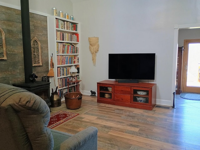 living room with wood finished floors, a wood stove, and baseboards