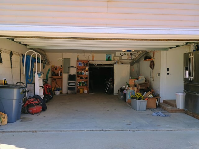 garage featuring fridge with ice dispenser and electric panel