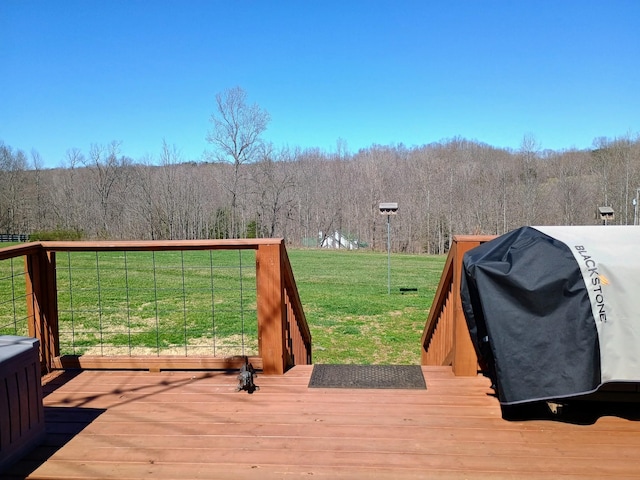 deck with a lawn, a grill, and a view of trees