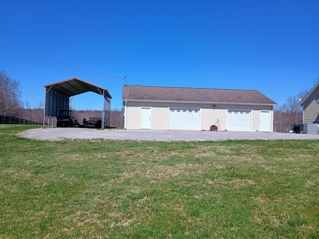 exterior space with a detached carport, a detached garage, fence, a lawn, and an outdoor structure