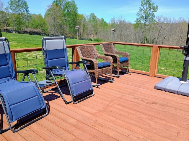 deck with fence, a lawn, and a forest view