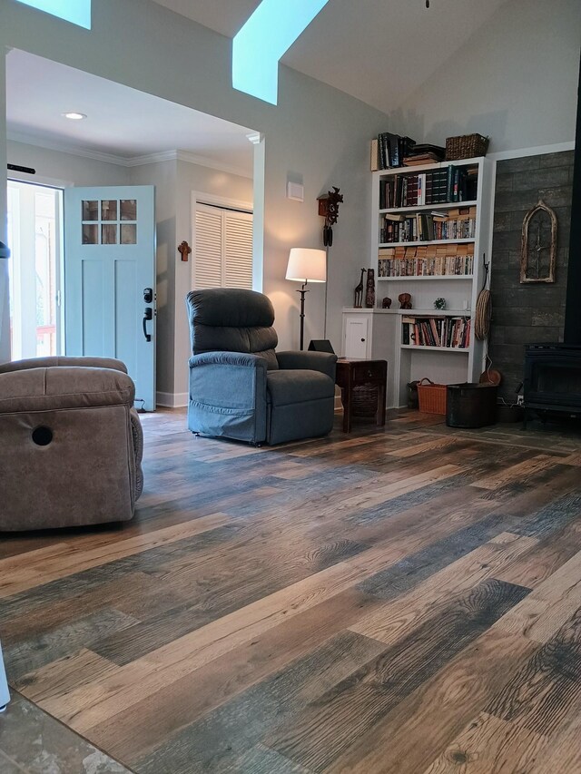 living room with ornamental molding, lofted ceiling, wood finished floors, and a wood stove