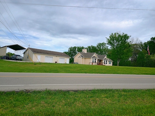 view of front of home with a detached carport, a front yard, and a garage