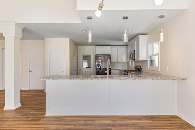 1106 Roseland Dr, Columbia, TN 38401 - kitchen with stainless steel appliances, light stone counters, pendant lighting, a peninsula, and wood finished floors