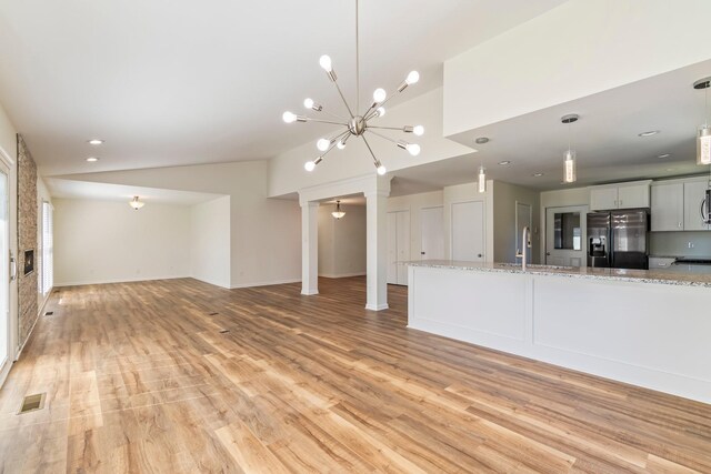 1106 Roseland Dr, Columbia, TN 38401 - unfurnished living room featuring vaulted ceiling, a sink, a chandelier, light wood-type flooring, and visible vents