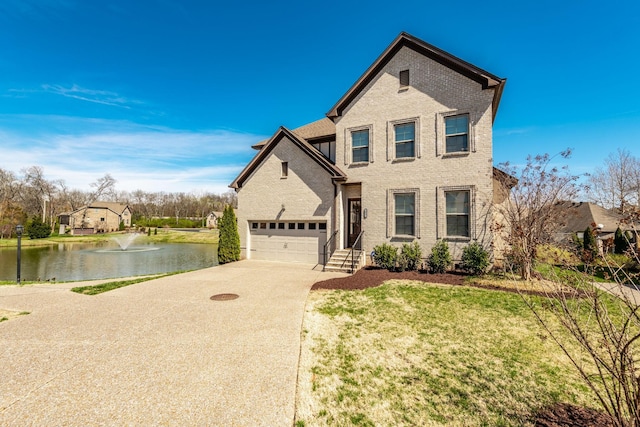 traditional-style home featuring brick siding, concrete driveway, a garage, and a water view