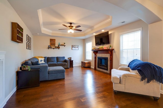 living area featuring a healthy amount of sunlight, a tiled fireplace, and a tray ceiling
