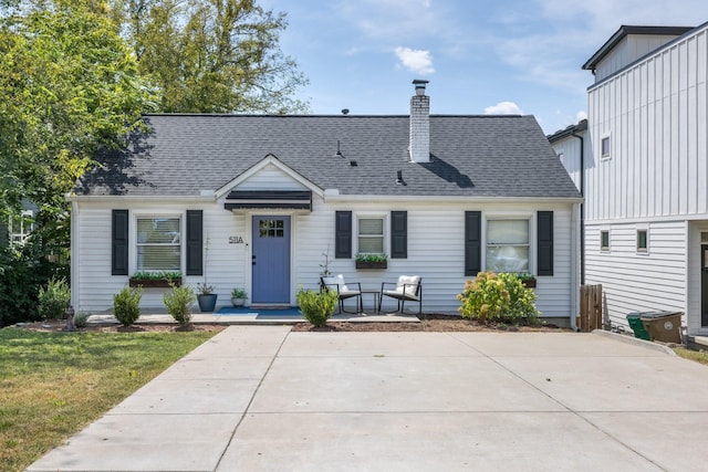 view of front of house with a front yard, roof with shingles, and a chimney