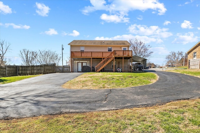 back of property featuring aphalt driveway, fence, stairway, and a yard