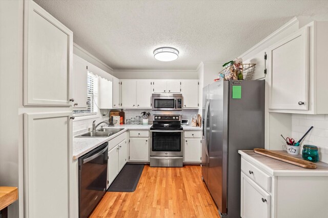 kitchen with white cabinetry, light countertops, a sink, and stainless steel appliances