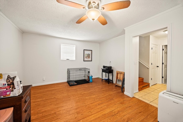 miscellaneous room featuring a textured ceiling, crown molding, light wood-style floors, and a ceiling fan