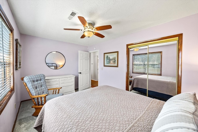 carpeted bedroom featuring visible vents, a closet, ceiling fan, and a textured ceiling