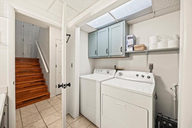 laundry room featuring light tile patterned floors, cabinet space, and washer and clothes dryer