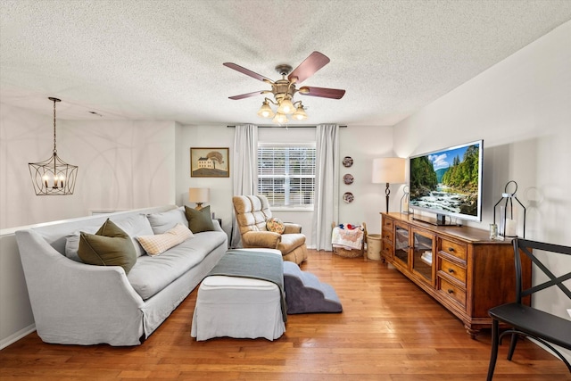 living area featuring ceiling fan with notable chandelier, hardwood / wood-style flooring, and a textured ceiling
