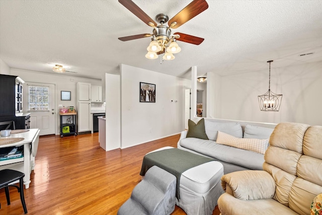 living room featuring a textured ceiling, light wood-style floors, and a ceiling fan