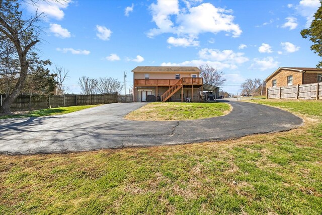 rear view of house with fence, stairs, aphalt driveway, a garage, and a yard