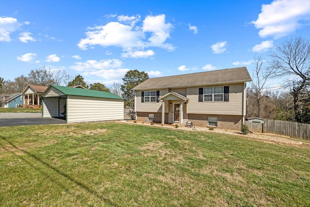 split foyer home with an outbuilding, driveway, fence, and a front lawn