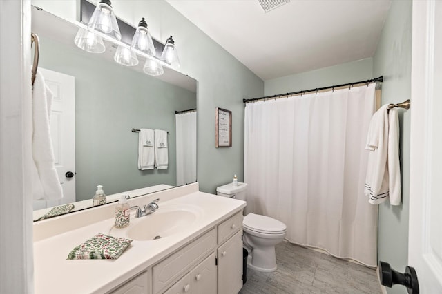 bathroom featuring toilet, vanity, and visible vents