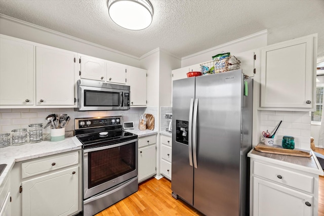 kitchen featuring crown molding, light wood finished floors, stainless steel appliances, tasteful backsplash, and white cabinetry