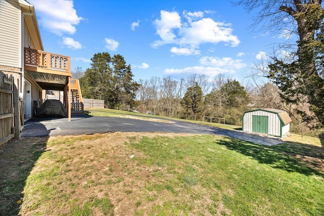 view of yard featuring an outbuilding, fence, stairs, a wooden deck, and a storage unit