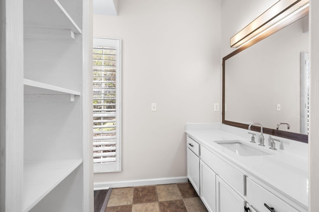 bathroom with vanity, baseboards, and stone finish flooring