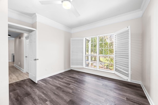 spare room featuring dark wood finished floors, baseboards, crown molding, and a ceiling fan