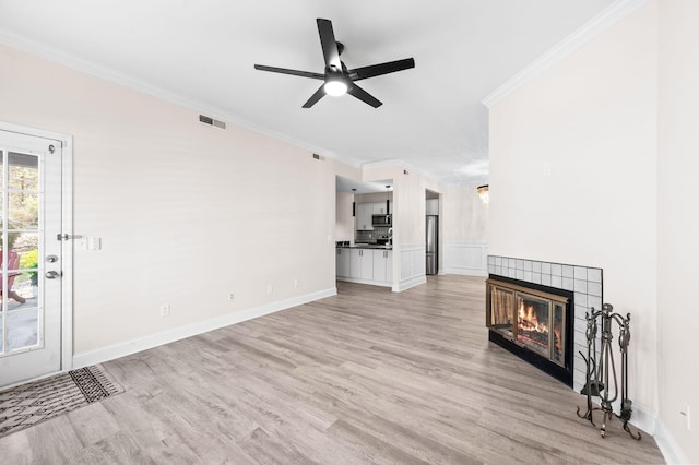 unfurnished living room featuring visible vents, a fireplace, ceiling fan, ornamental molding, and light wood-style floors