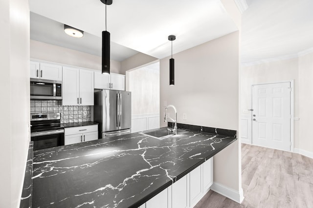 kitchen with decorative backsplash, light wood-style floors, white cabinets, stainless steel appliances, and a sink