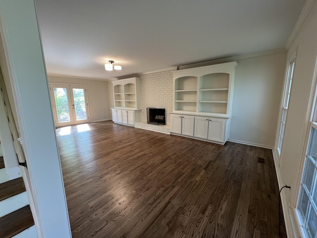 unfurnished living room with ornamental molding, baseboards, a brick fireplace, and dark wood-style floors