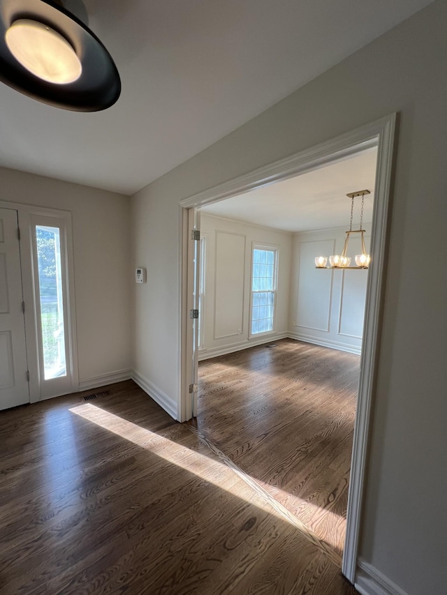foyer entrance with a notable chandelier, dark wood finished floors, and baseboards