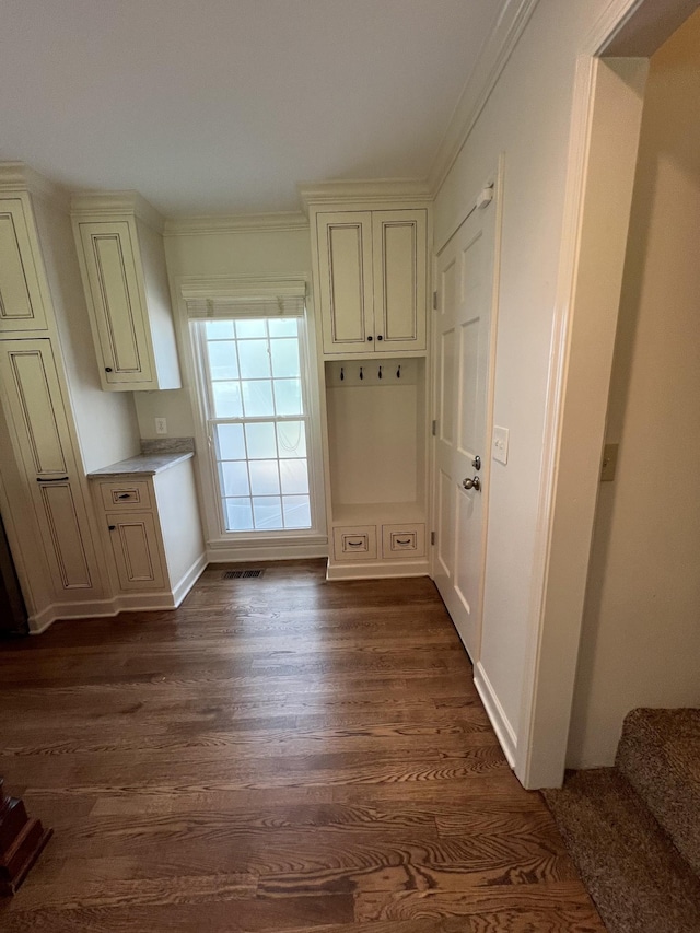 interior space with ornamental molding, dark wood-style floors, visible vents, and stairs